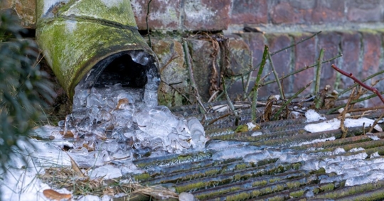 frozen gutter covered with icicles in winter
