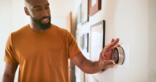Man Adjusting Digital Central Heating Thermostat at Home