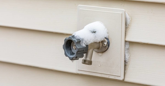Outdoor water spigot covered in snow during winter