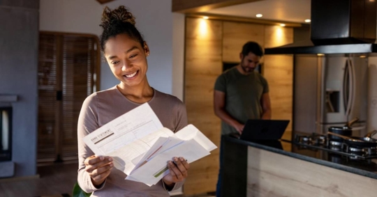 Woman at home looking at a utility bill that came in the mail